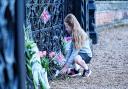 A young girl lays a floral tribute outside the Sandringham Estate