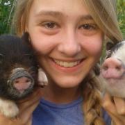 Megan Clarke holding up her pets pigs Tammy and Ruby